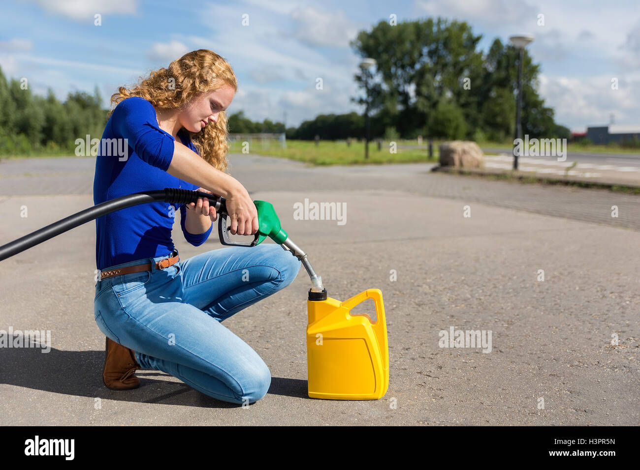 Dutch femme jaune peut remplir avec de l'essence à l'extérieur du flexible Banque D'Images