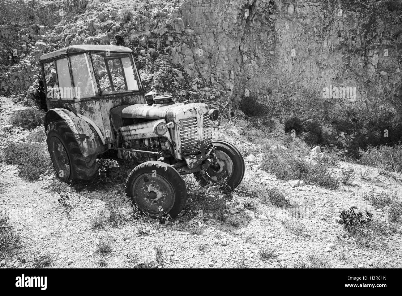 Vieux tracteur rouillé abandonné se dresse sur la prairie. Photo en noir et blanc Banque D'Images