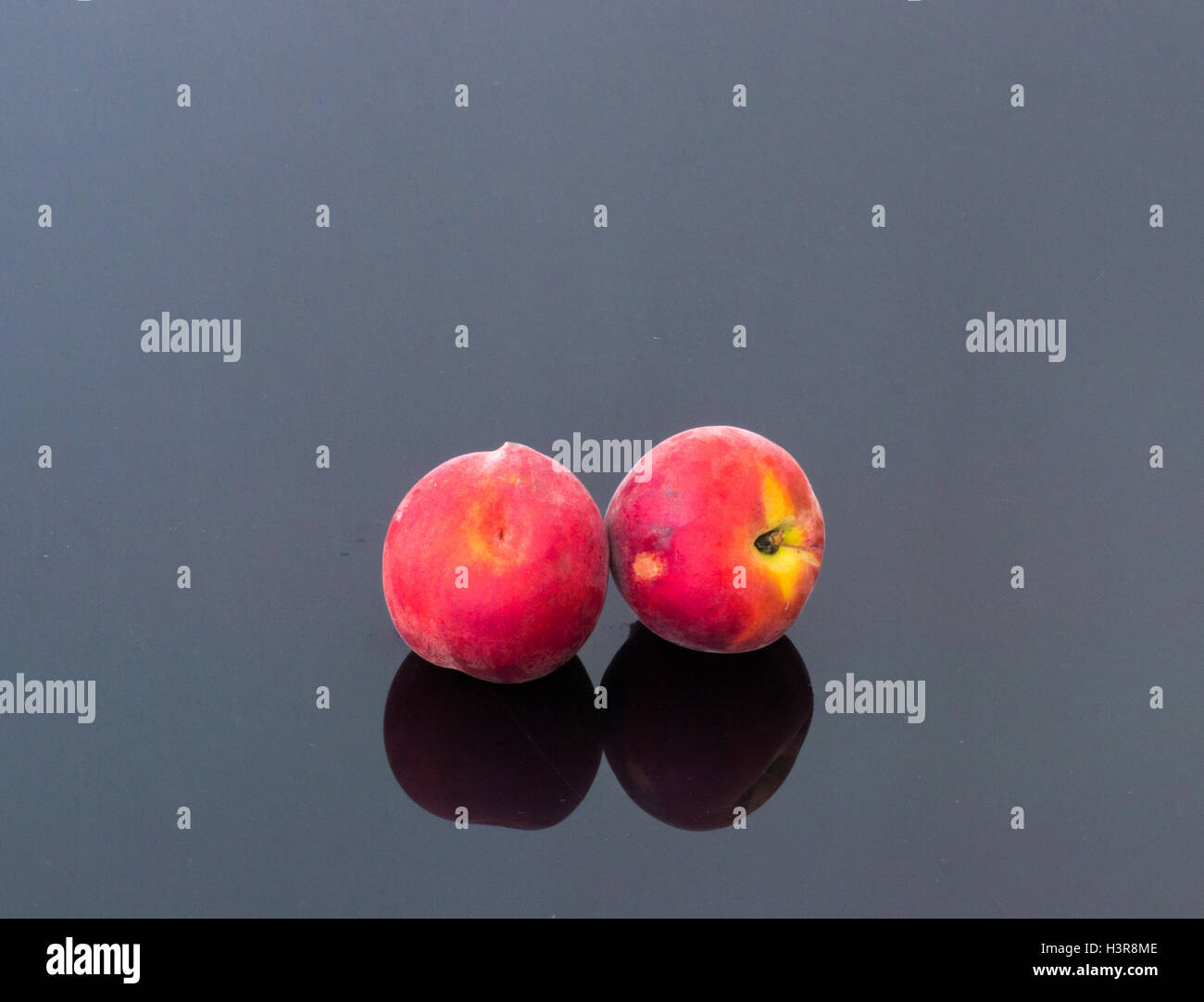 Deux pêches biologiques frais sur une table en verre Banque D'Images