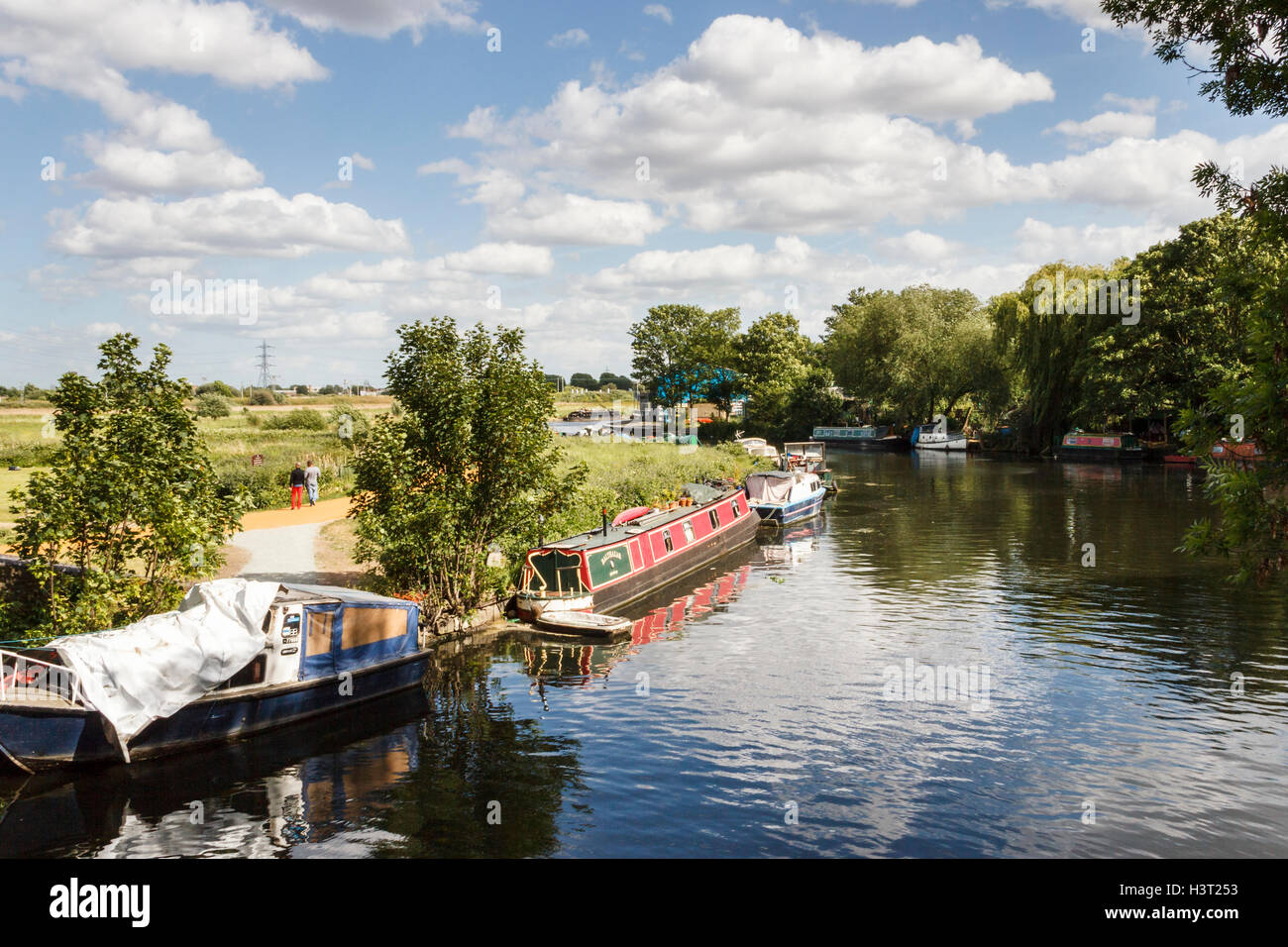 Vue en aval du Horse Shoe Bridge de bateaux étroits amarrés sur la rivière Lea à Upper Clapton, Londres, Royaume-Uni, Walthamstow Marshes sur la gauche Banque D'Images