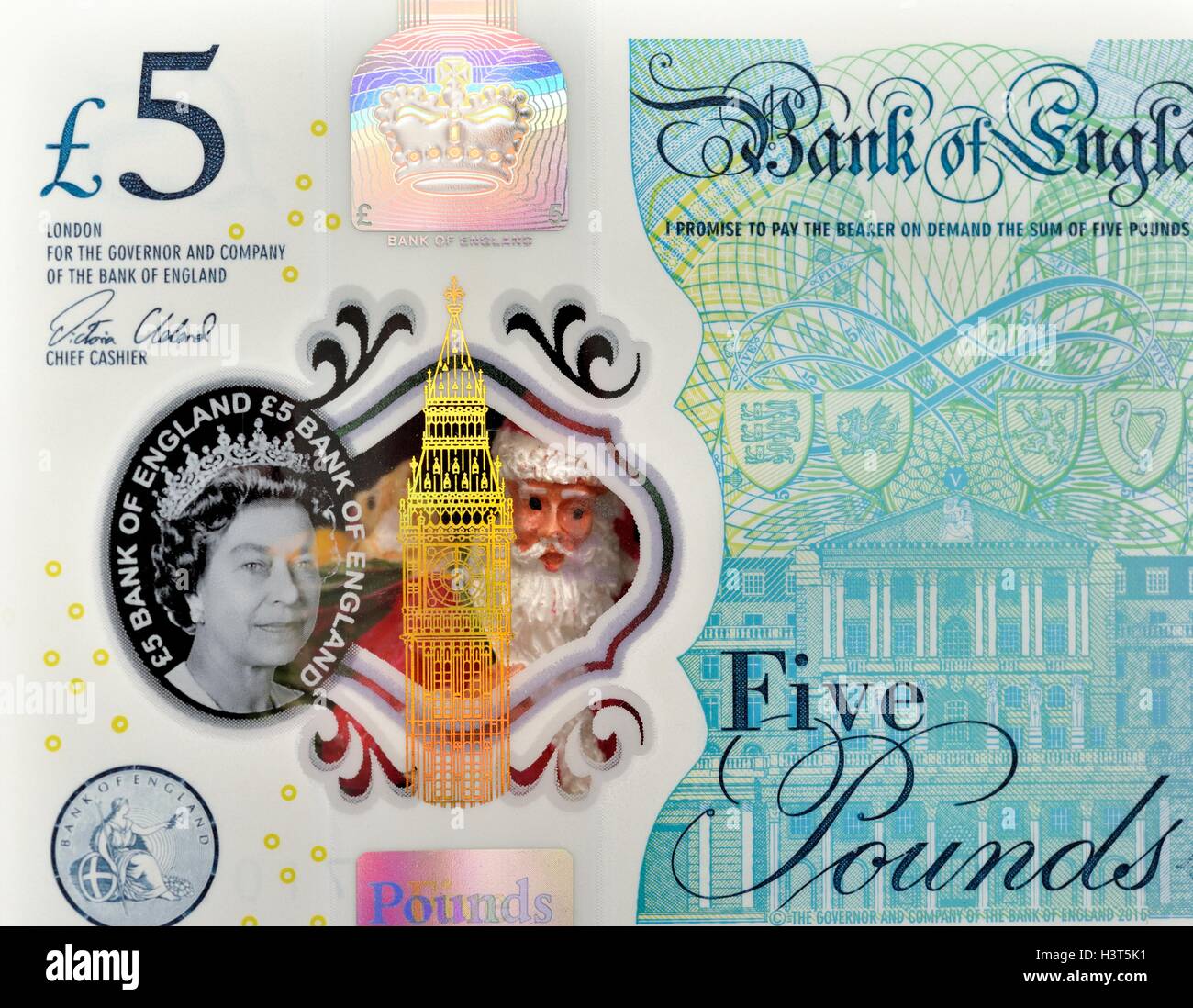 Un santa claus figurine regardant à travers la fenêtre transparente d'un nouveau cinq livre England UK Banque D'Images