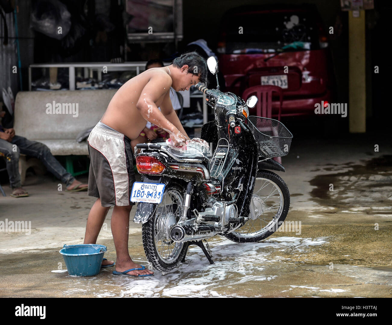 L'homme se lave le cyclomoteur, Phnom Penh, Cambodge Banque D'Images