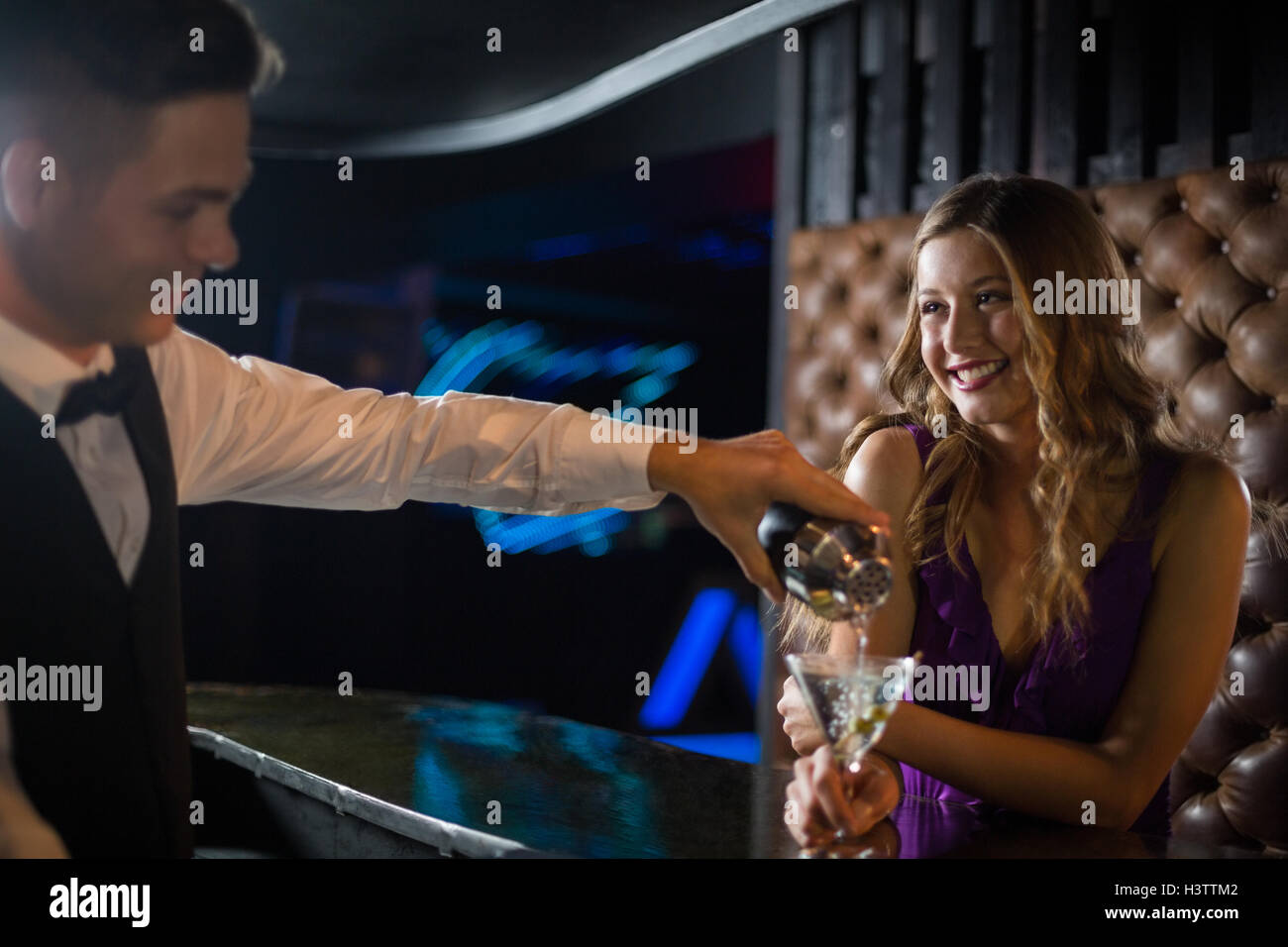 Waiter pouring cocktail dans un verre au comptoir du bar femme Banque D'Images