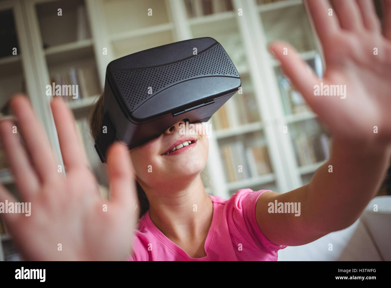 Girl looking through casque de réalité virtuelle dans la salle de séjour Banque D'Images