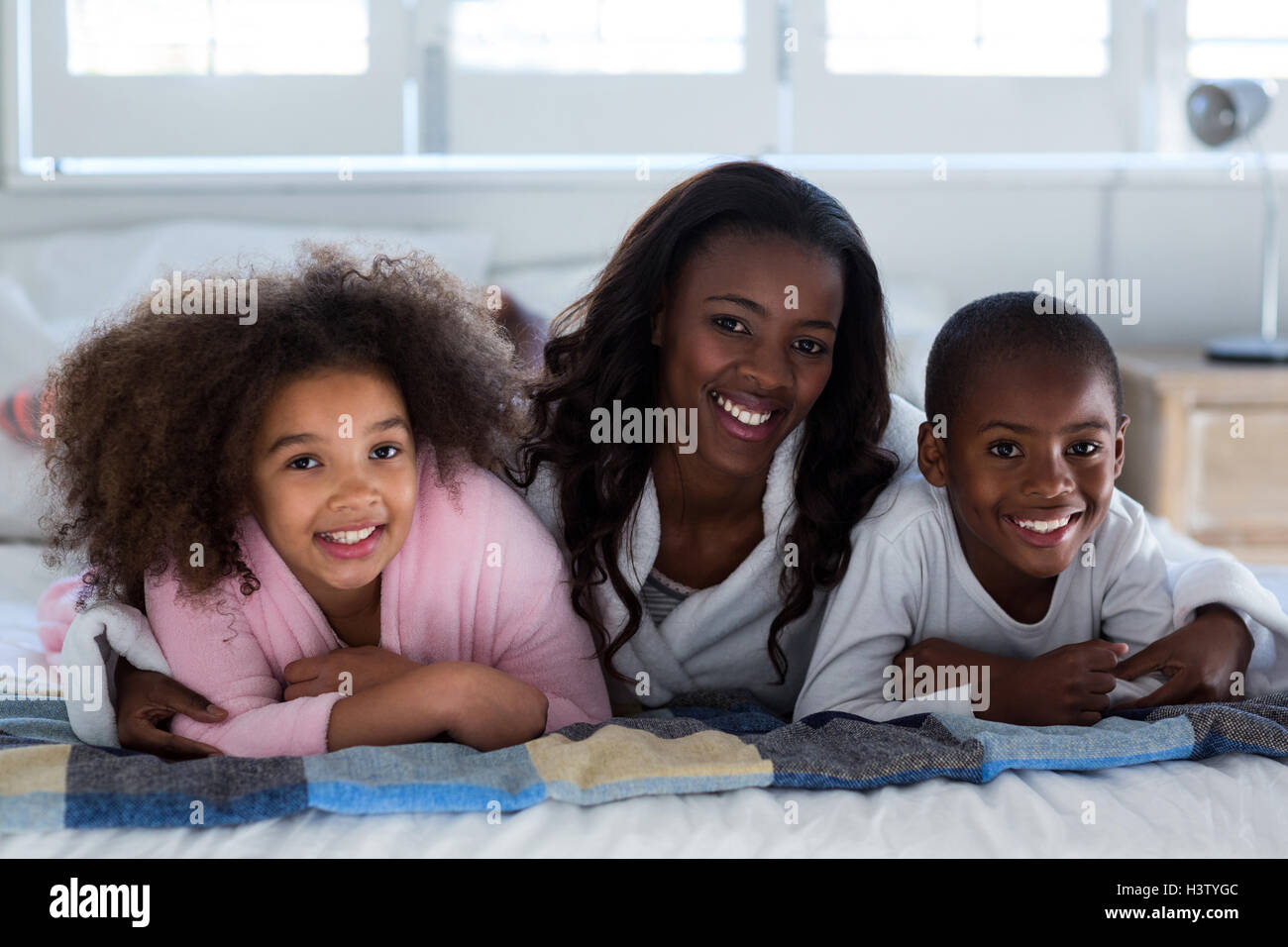 Mère avec leurs enfants lying on bed Banque D'Images