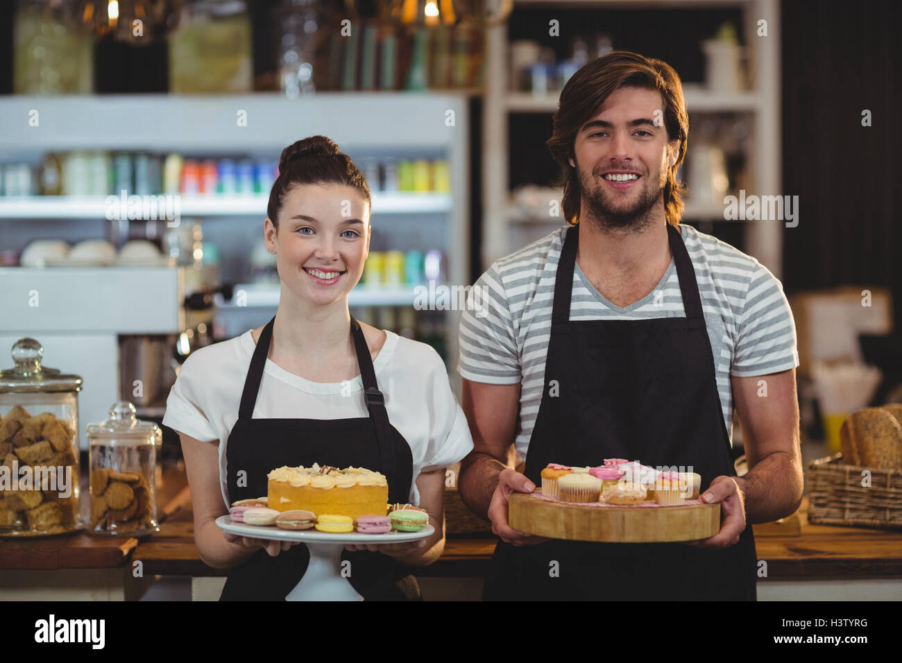 Portrait de serveur et serveuse holding a tray of cupcakes Banque D'Images