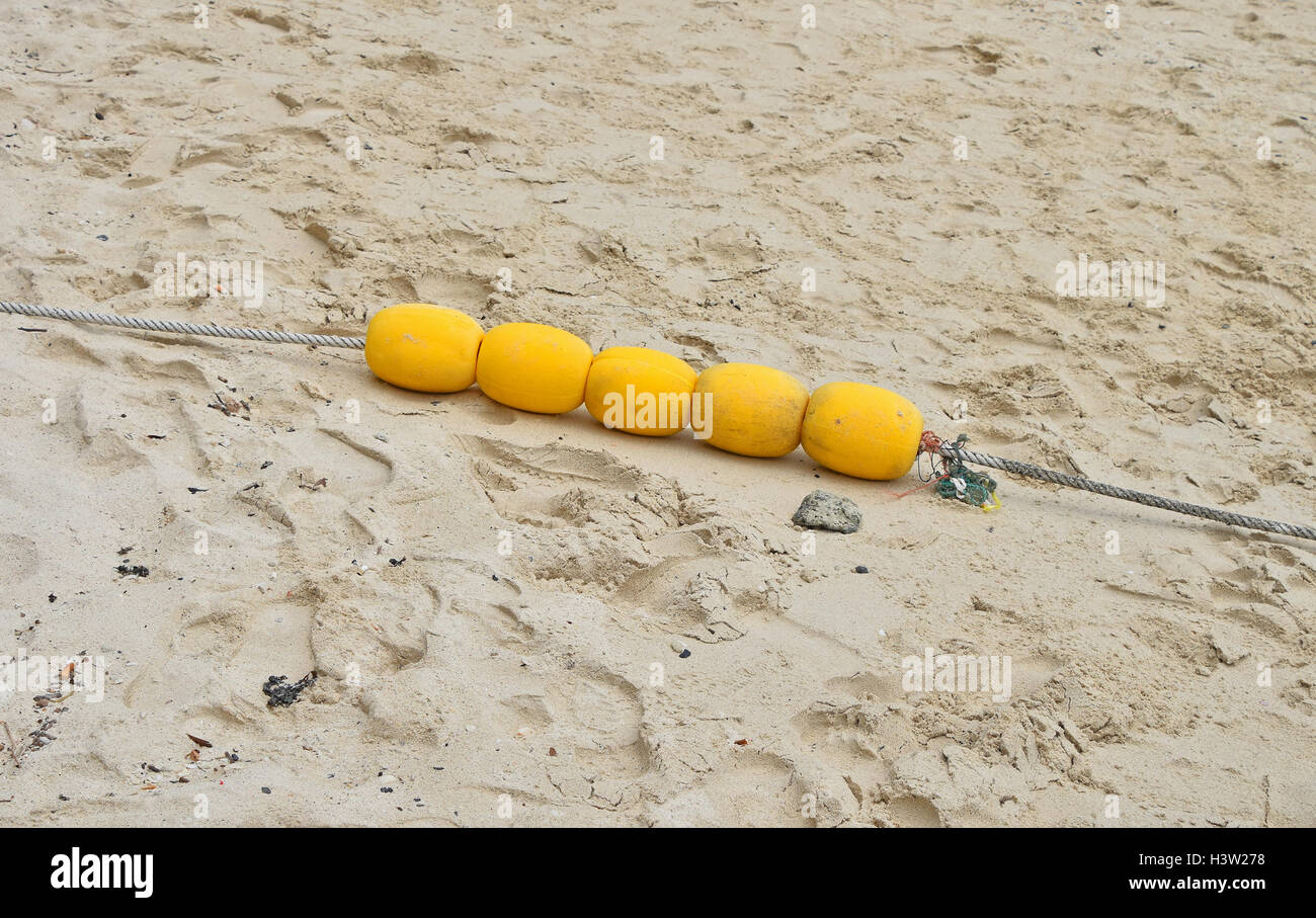 Quatre bouées de marquage jaune mer polystyrène avec groupe remorquage câble sur le sable humide de la plage mer Banque D'Images