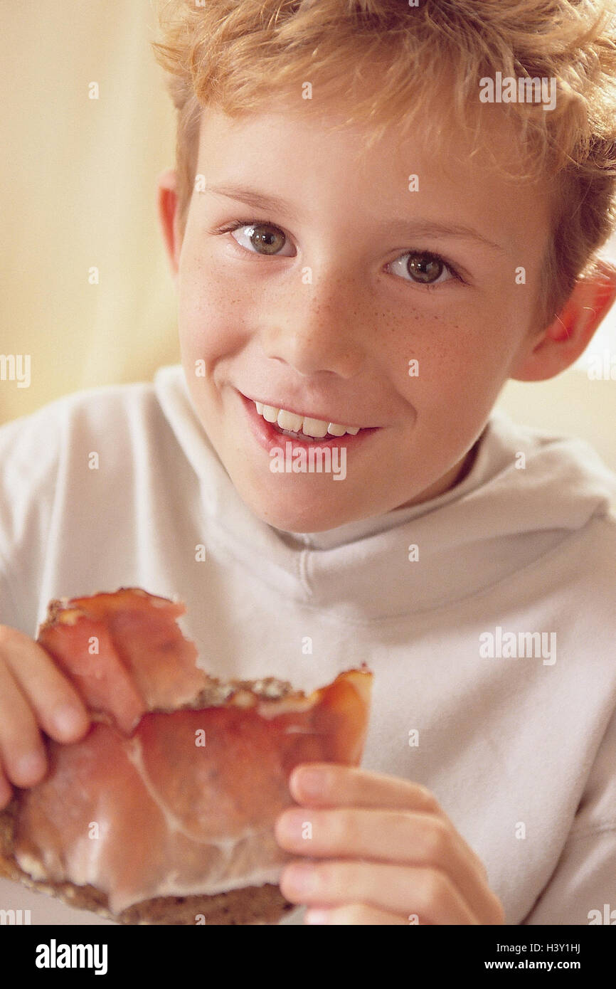 Garçon, heureux, sandwich au jambon, portrait, intérieur, à la maison,  enfant, rousse, manger, pain, livres, bacon, bacon, jambon, cru, la faim,  l'appétit, savoureux, du pain complet, une tranche de pain, de gaieté,