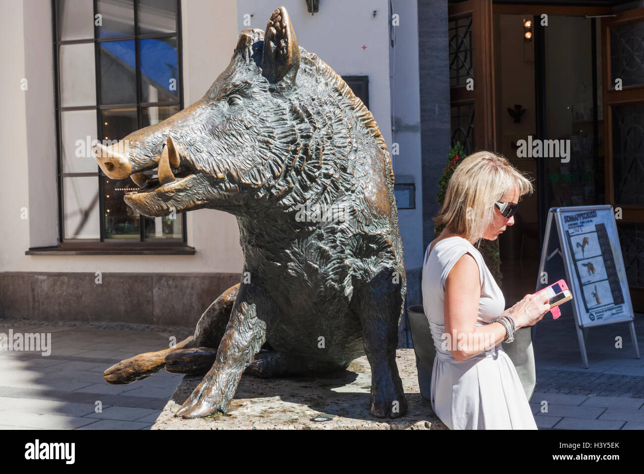 Germany, Bavaria, Munich, rue Commerçante Kaufingerstrasse, Statue de sanglier et de la femme avec l'iPhone Banque D'Images