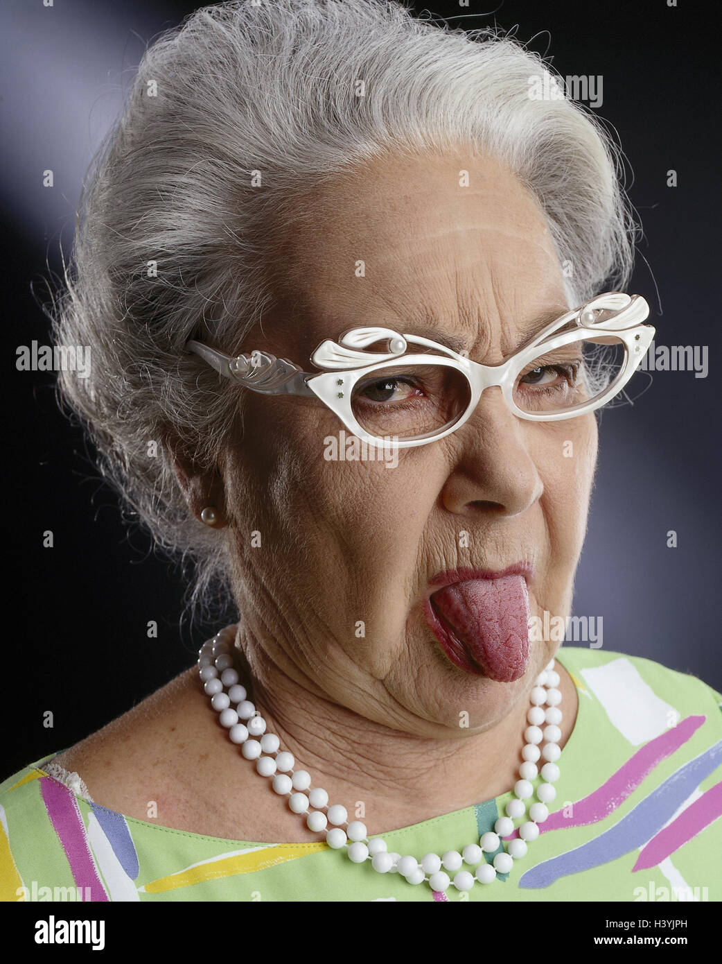 Senior, lunettes, jouer du visage, de la langue du pensionné, passages Rau, vieille femme, aux cheveux gris, aide visuelle, collier de perle, T-shirt, insolents, des insultes, de la décence Banque D'Images