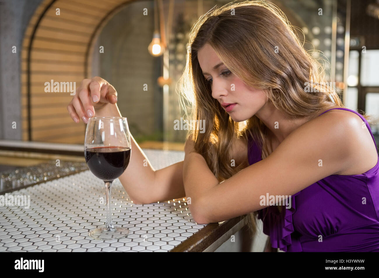 Femme sérieuse ayant le vin rouge au comptoir du bar Banque D'Images