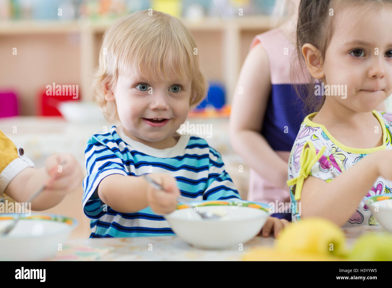 Les enfants mangeant de plaques dans day care centre Banque D'Images