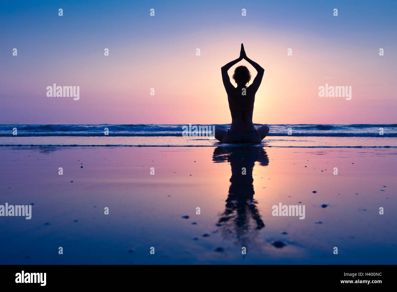 Jeune femme en bonne santé pratiquant le yoga sur la plage Banque D'Images