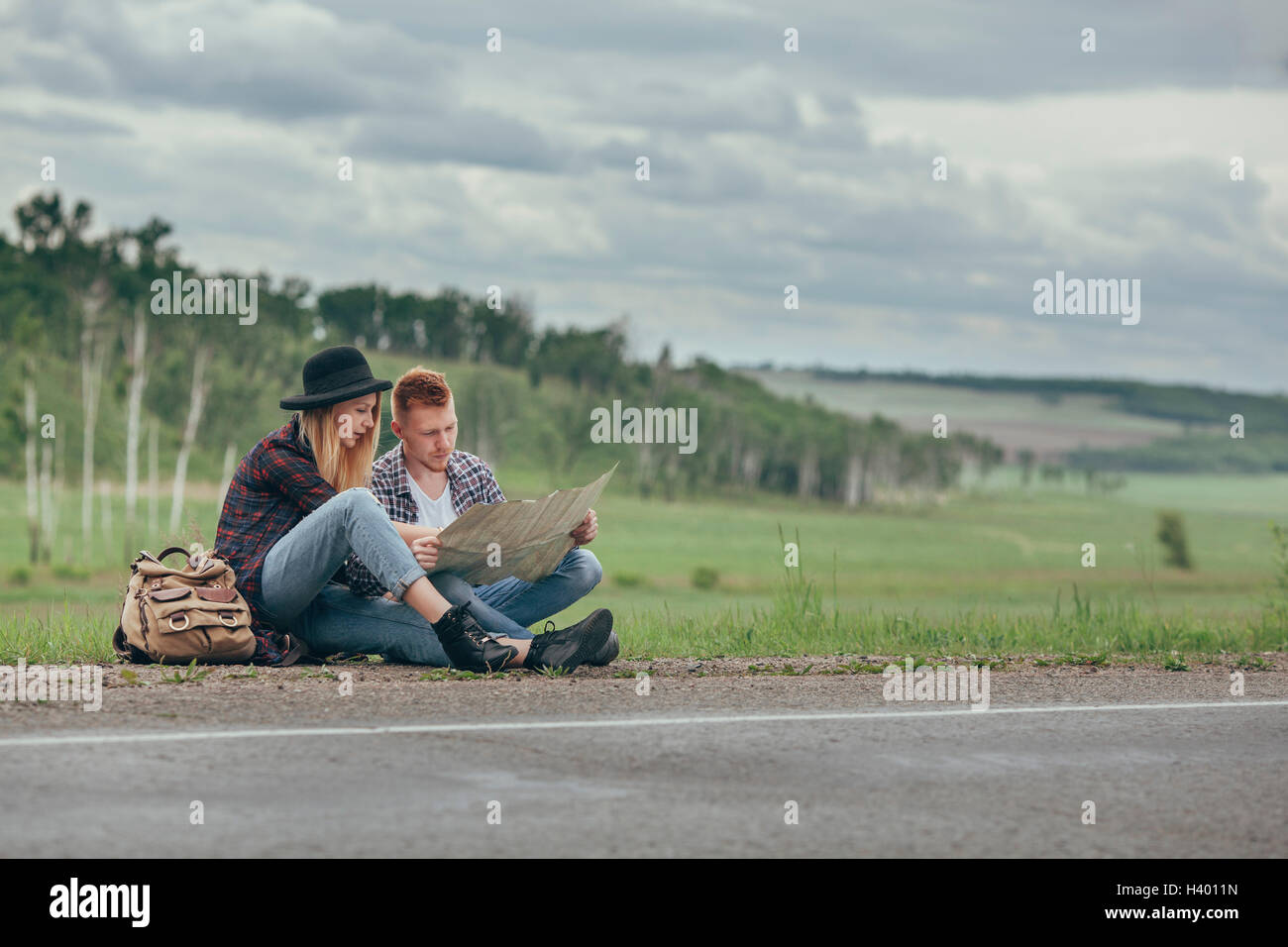 Couple assis sur la route contre le ciel Banque D'Images