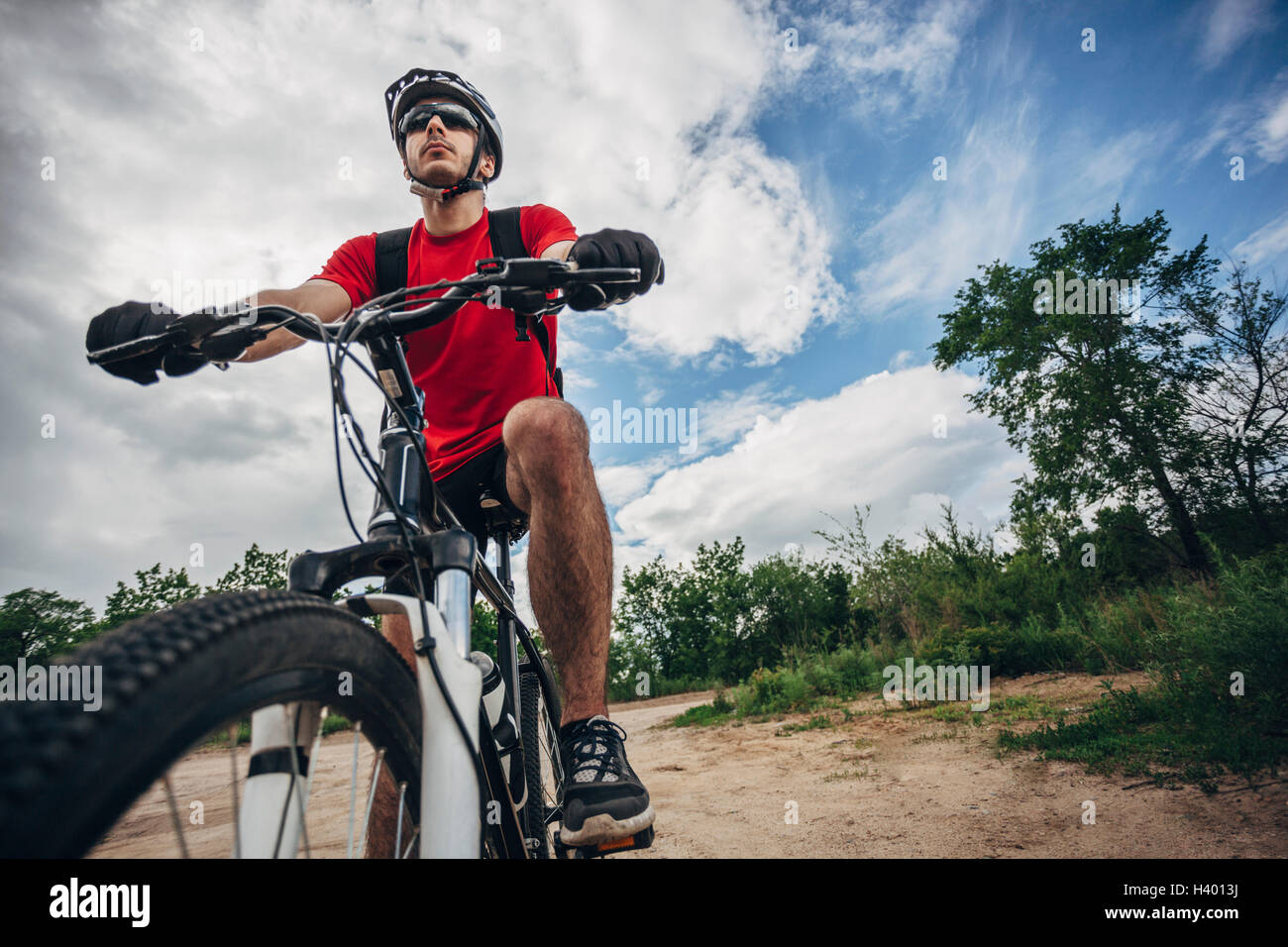 Low angle view of mountain biker riding on dirt road against sky Banque D'Images
