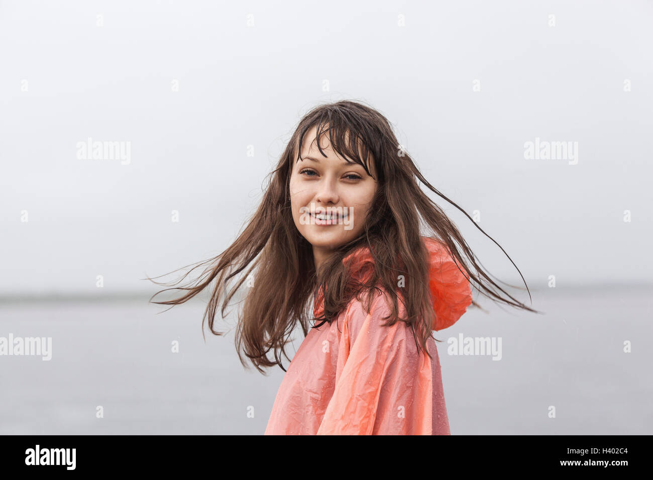Portrait of smiling woman wearing raincoat debout contre un ciel clair Banque D'Images