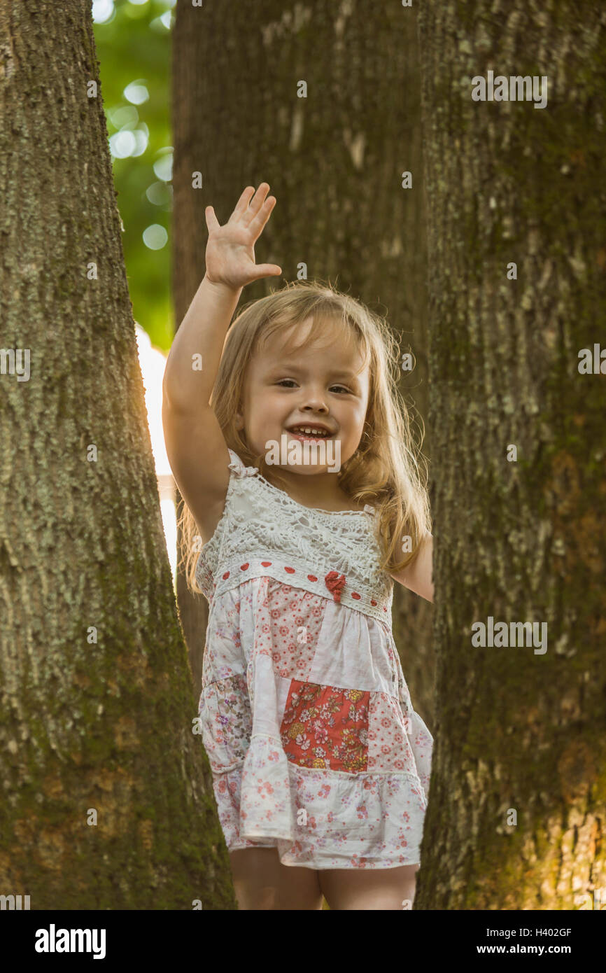 Portrait of cheerful girl gesticulant debout au milieu d'arbres à park Banque D'Images