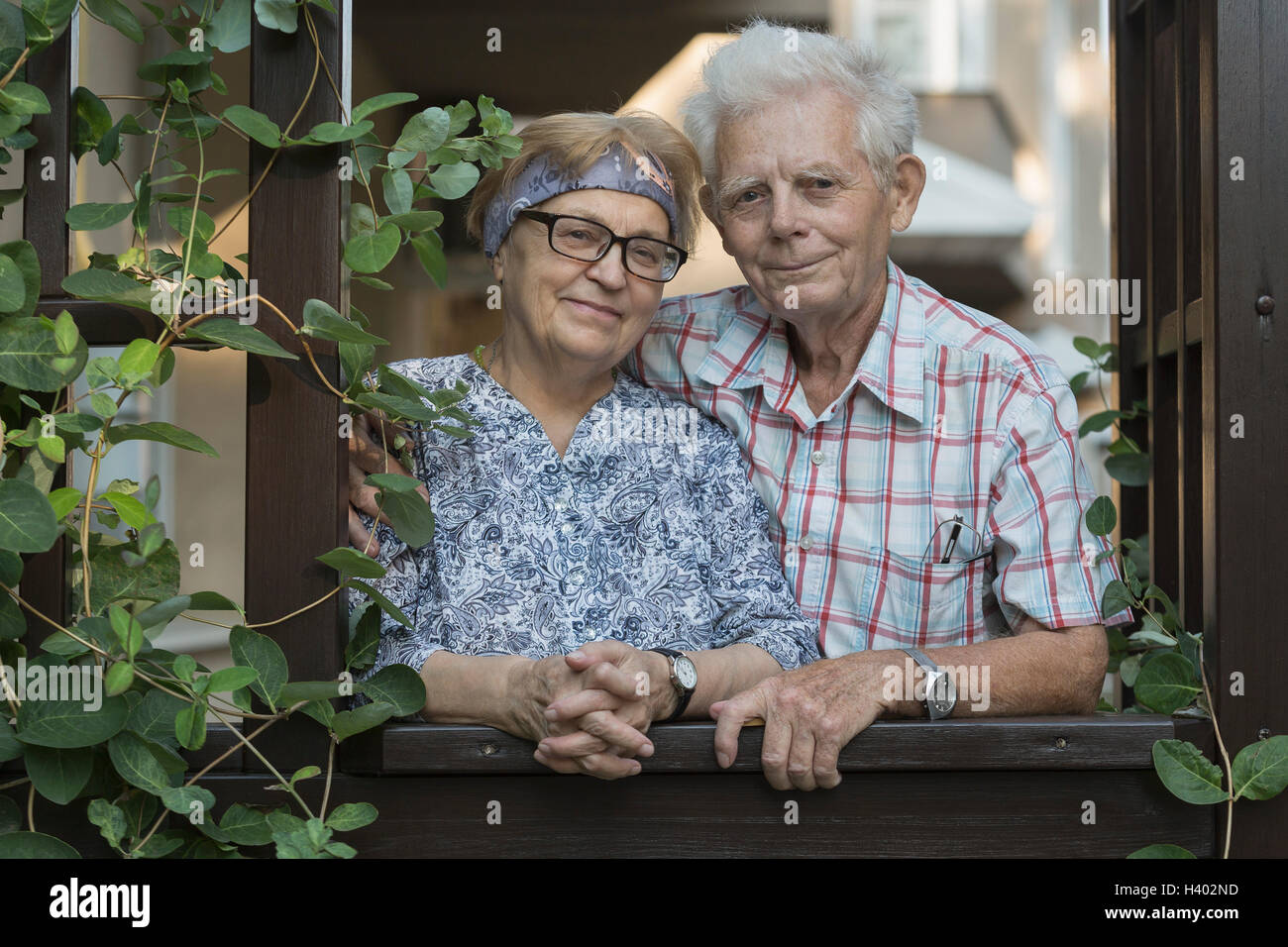 Portrait of smiling senior woman standing at window Banque D'Images
