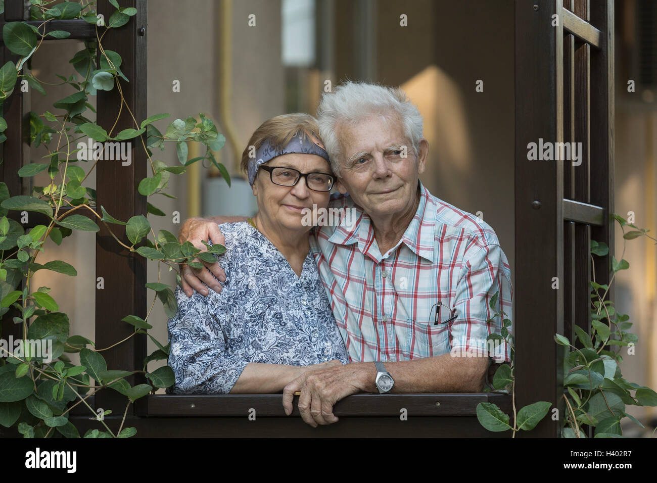 Thoughtful happy senior couple standing at window Banque D'Images