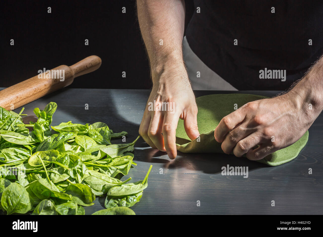 Portrait de l'homme vert à pétrir la pâte par basilics à table Banque D'Images