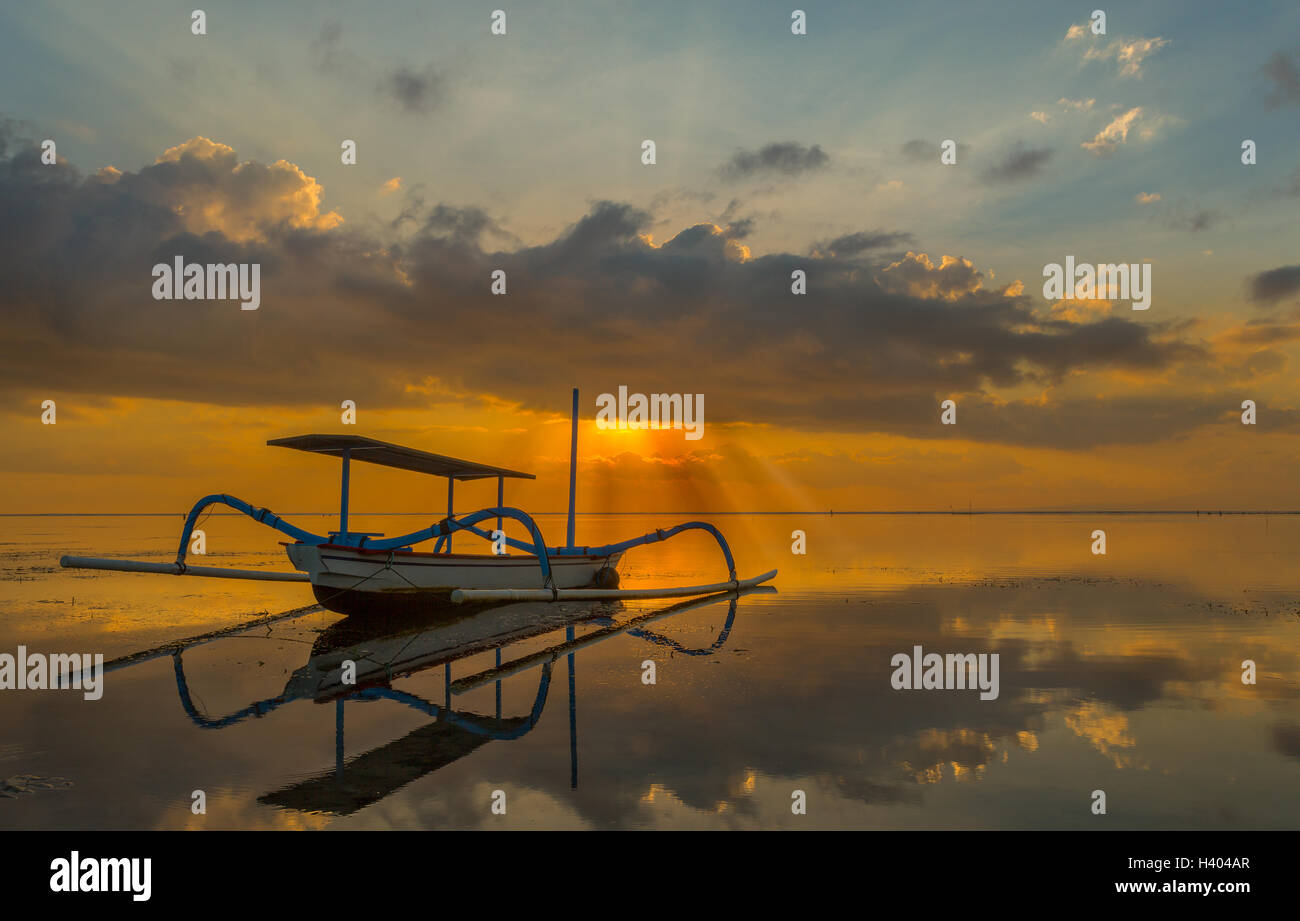 Bateau de pêche Jukung au coucher du soleil, de la plage de Sanur, Bali, Indonésie Banque D'Images