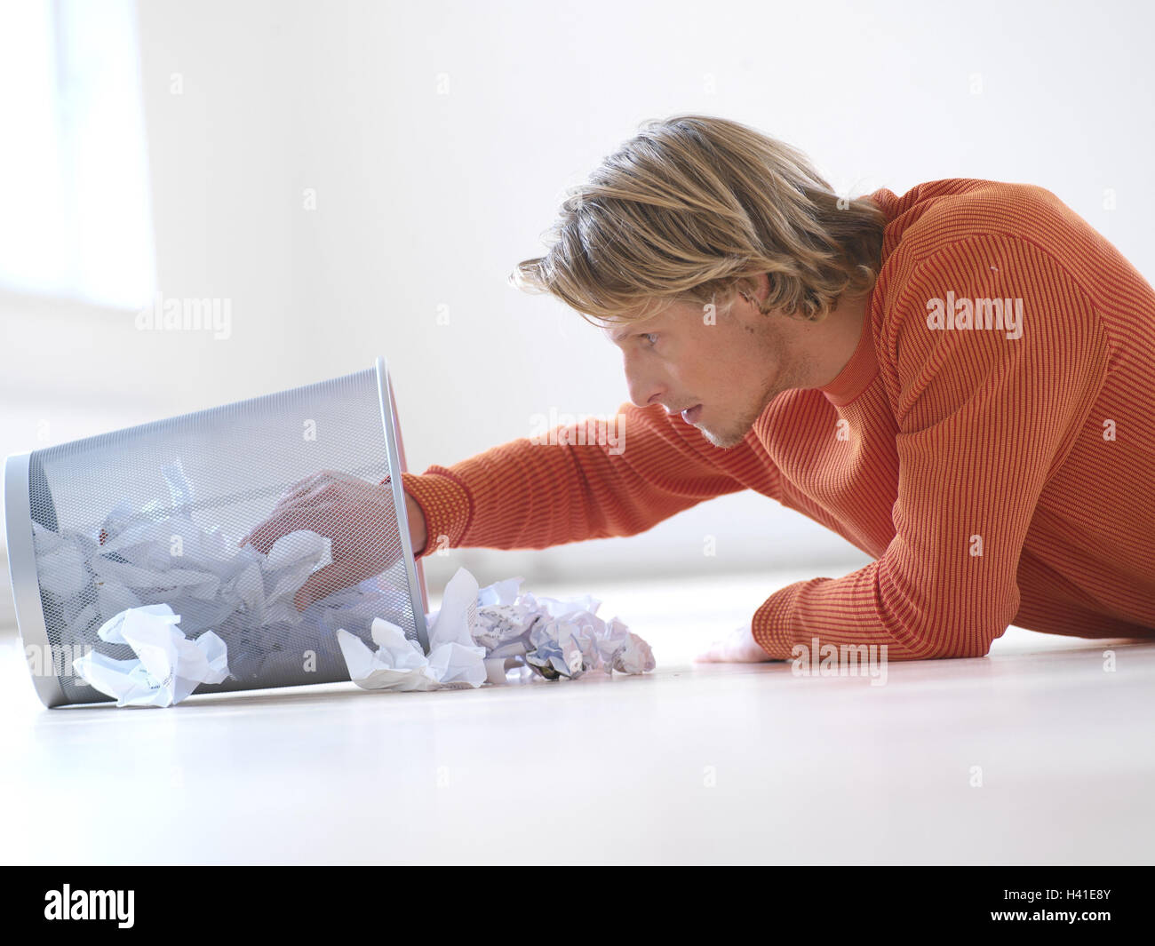 L'homme, corbeille, parcourir, étage, se trouvent les jeunes, blonde, lunettes, position abdominale, tendu, de concentrés, d'intérêts curieusement, au sérieux, les poubelles, les déchets de papier, creuser, fouiller dans, vous pouvez, choisir, documents, bases, de lettres, de documents, froisse, lo Banque D'Images