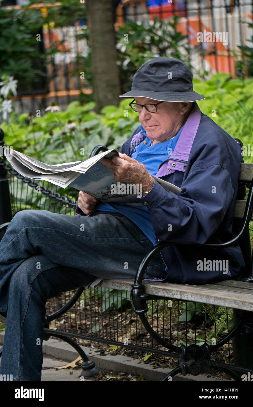 Un homme plus âgé, la lecture du New York Times sur un banc à Washington Square Park à Greenwich Village, New York City. Banque D'Images