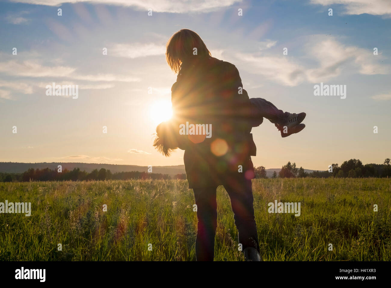 Femme transportant son in field at sunset Banque D'Images