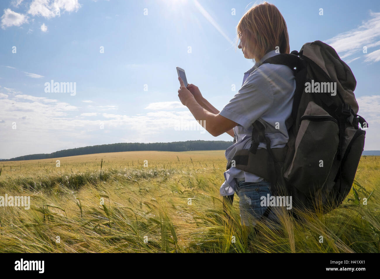 Caucasian woman standing in field using cell phone Banque D'Images