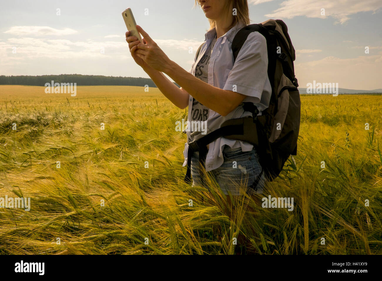 Caucasian woman standing in field using cell phone Banque D'Images