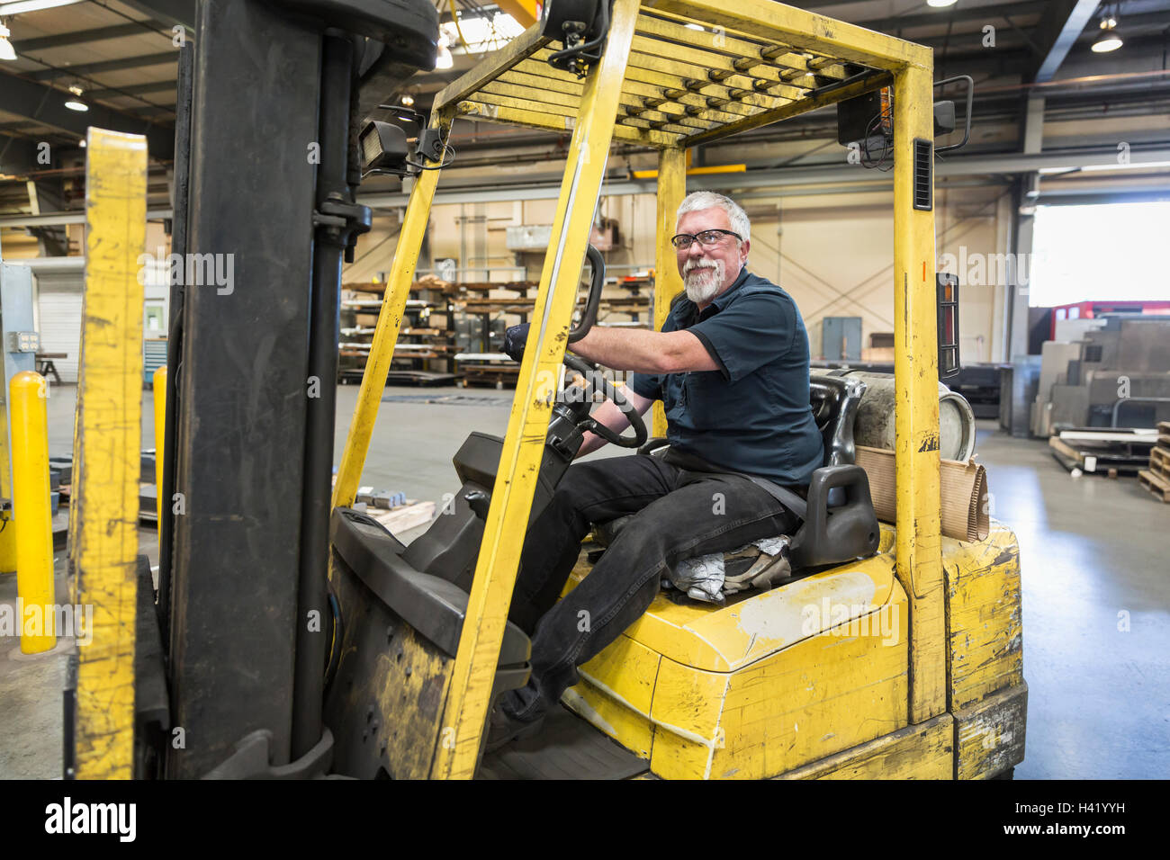 Caucasian worker driving forklift in factory Banque D'Images