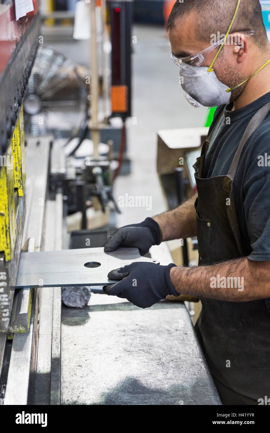 Hispanic worker wearing mask metal fabrication en usine Banque D'Images