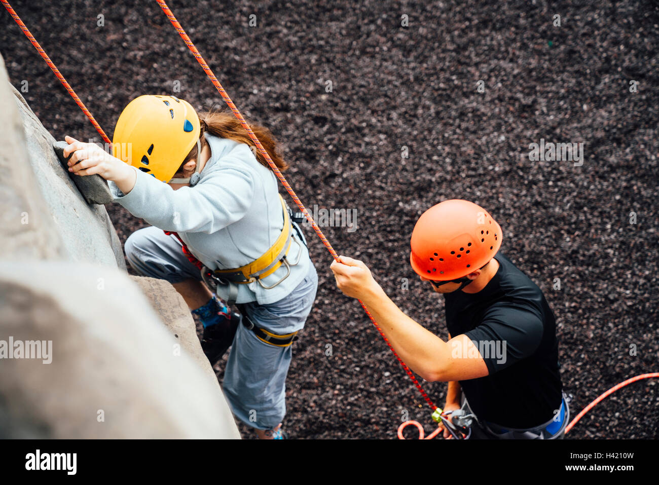 Caucasian man holding rope de woman climbing rock climbing wall Banque D'Images
