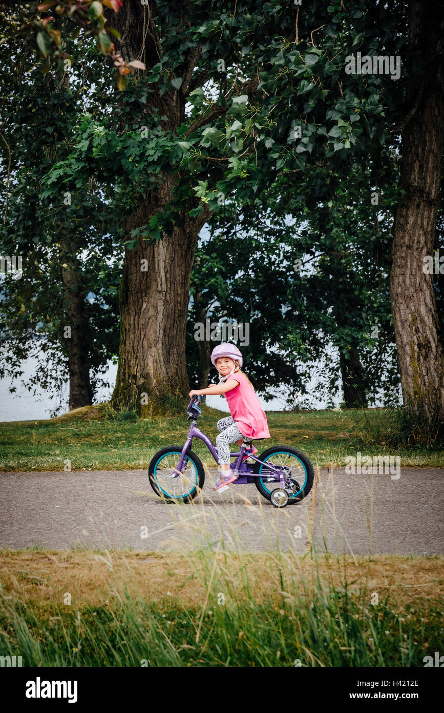 Mixed Race girl riding bicycle avec roues de formation Banque D'Images