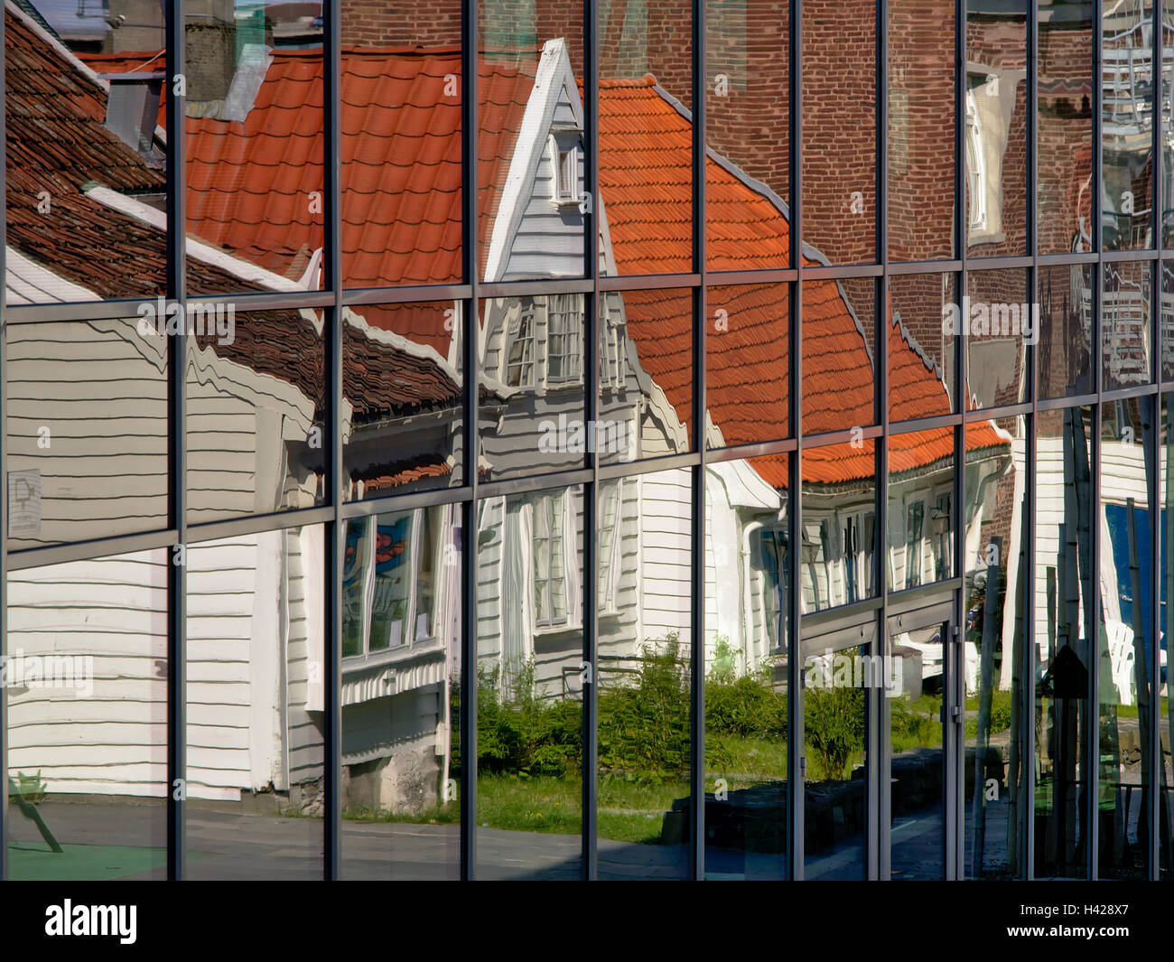 Reflet des maisons traditionnelles en bois peint en blanc dans des fenêtres d'un bâtiment moderne en verre et acier Banque D'Images