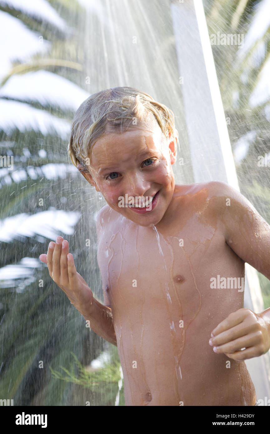 Garçon, souriant, douche de jardin, palmiers, demi-portrait, personnes,  enfants, vacances, vacances, vacances, vacances, plage de temps libre,  ensoleillée, l'eau, humide, jet d'eau, prendre une douche, douche, à  l'extérieur, heureux Photo Stock -