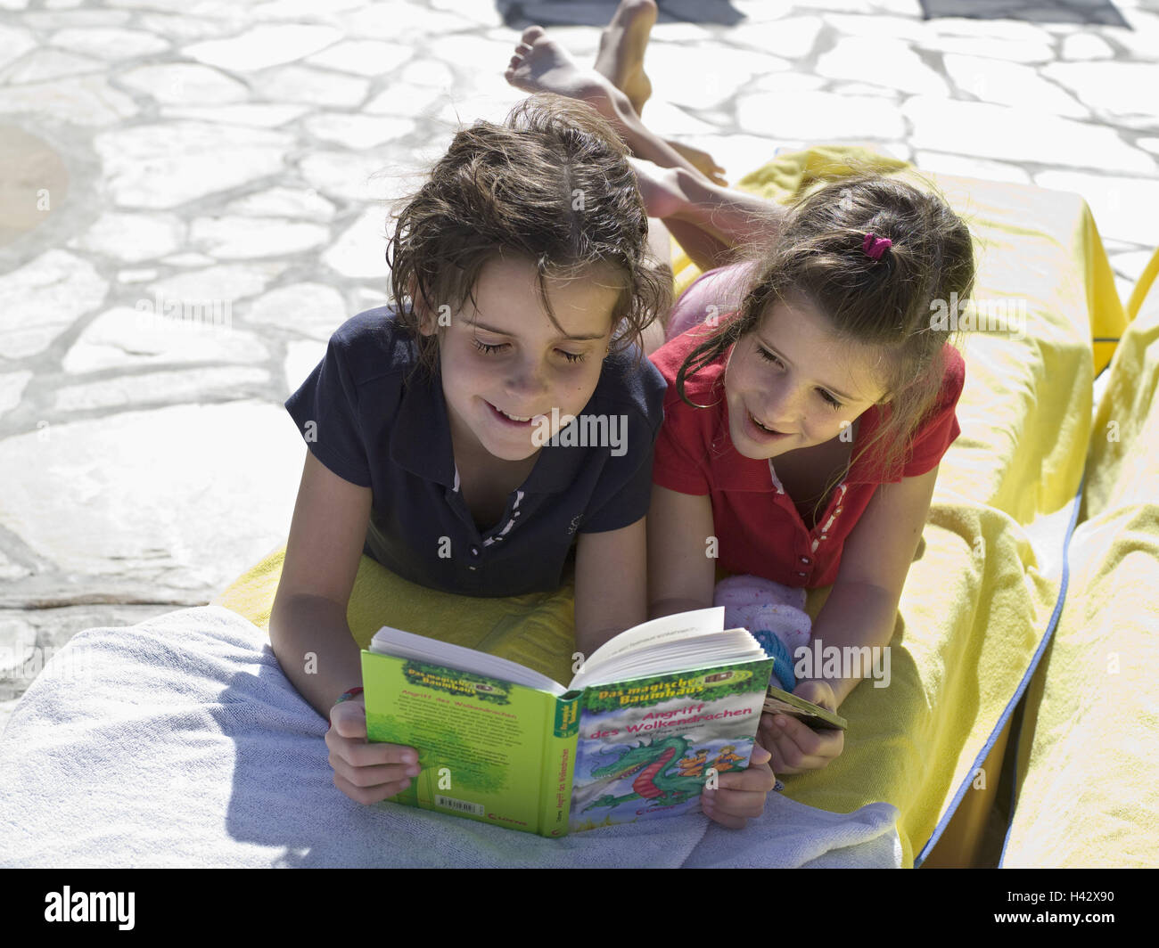 Les filles, jumeaux, 8 ans, se coucher, lisez le livre, modèle libéré, enfants, sœurs, personnes, deux, côte à côte, livre pour enfants, des histoires, des histoires d'enfant, fairy tales, excitante, profiter, récupérer, apprendre, temps de loisirs, hobby, vacances, banc solaire, soleil, Banque D'Images