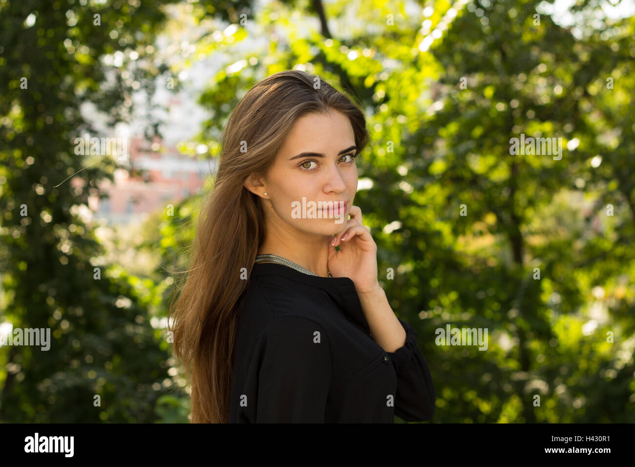 Jeune femme debout sidewise sur l'arrière-plan d'arbres Banque D'Images