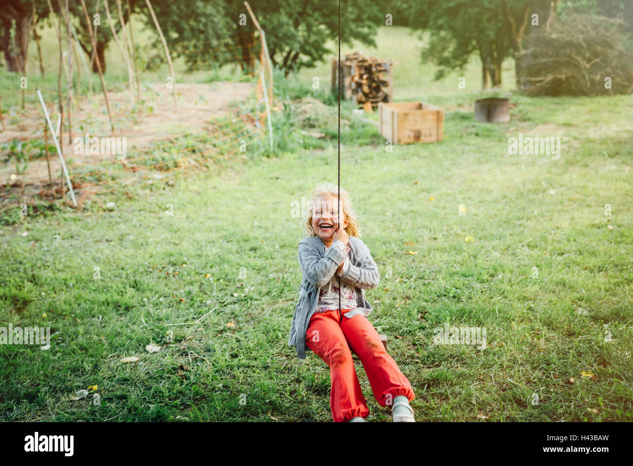 Smiling Caucasian girl on rope swing Banque D'Images