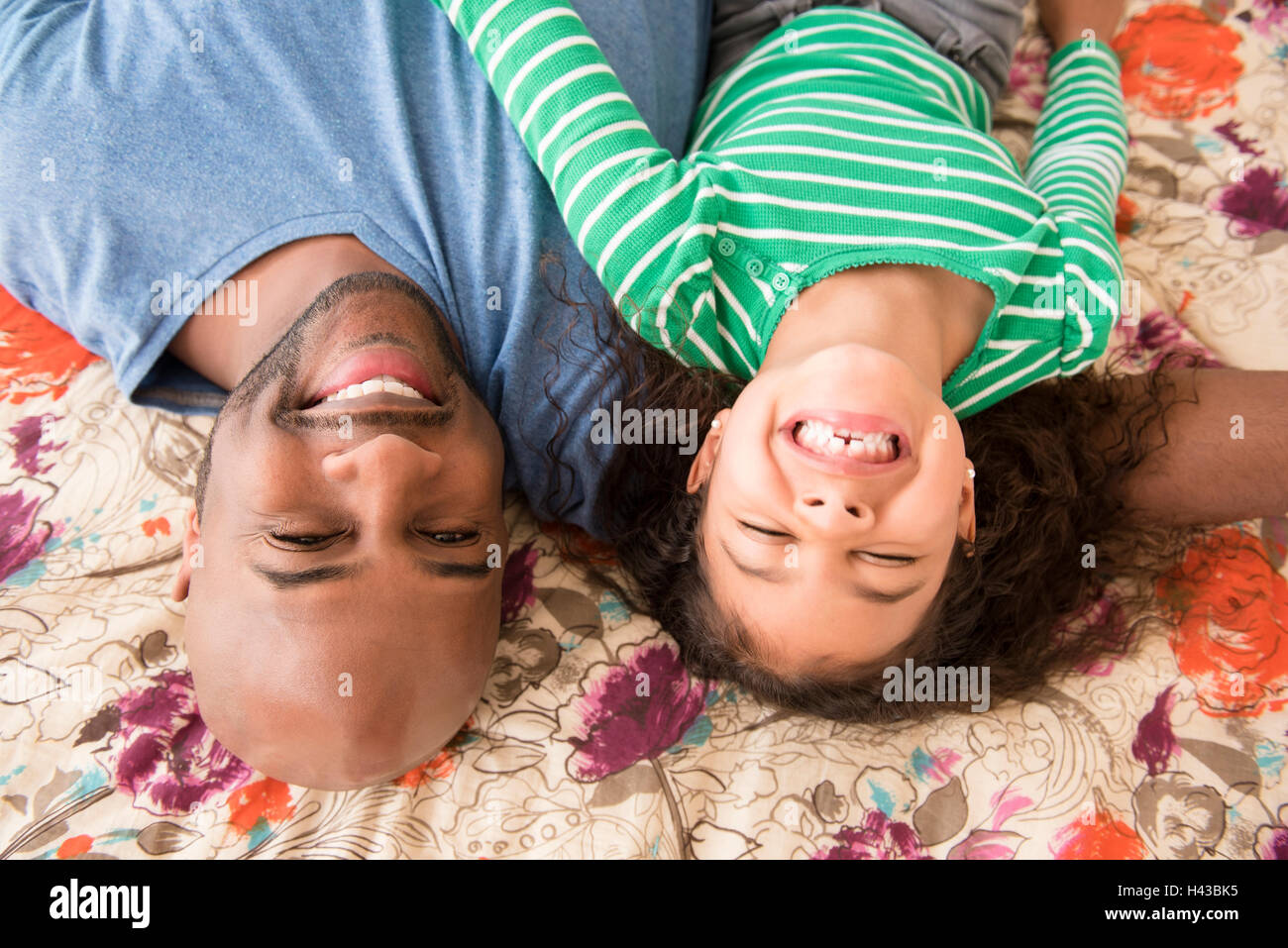 Smiling father and daughter laying on bed Banque D'Images