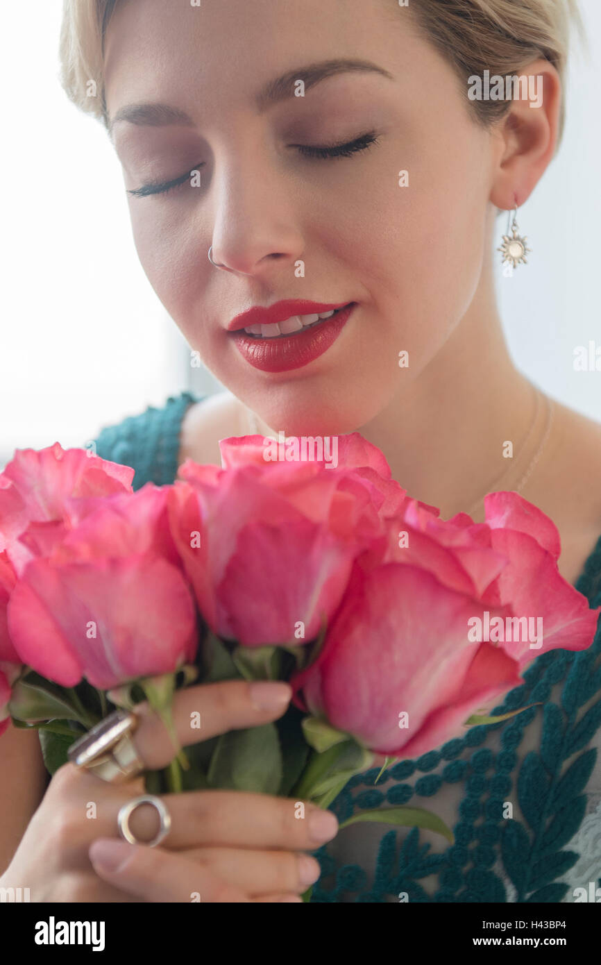 Caucasian woman smelling pink roses Banque D'Images