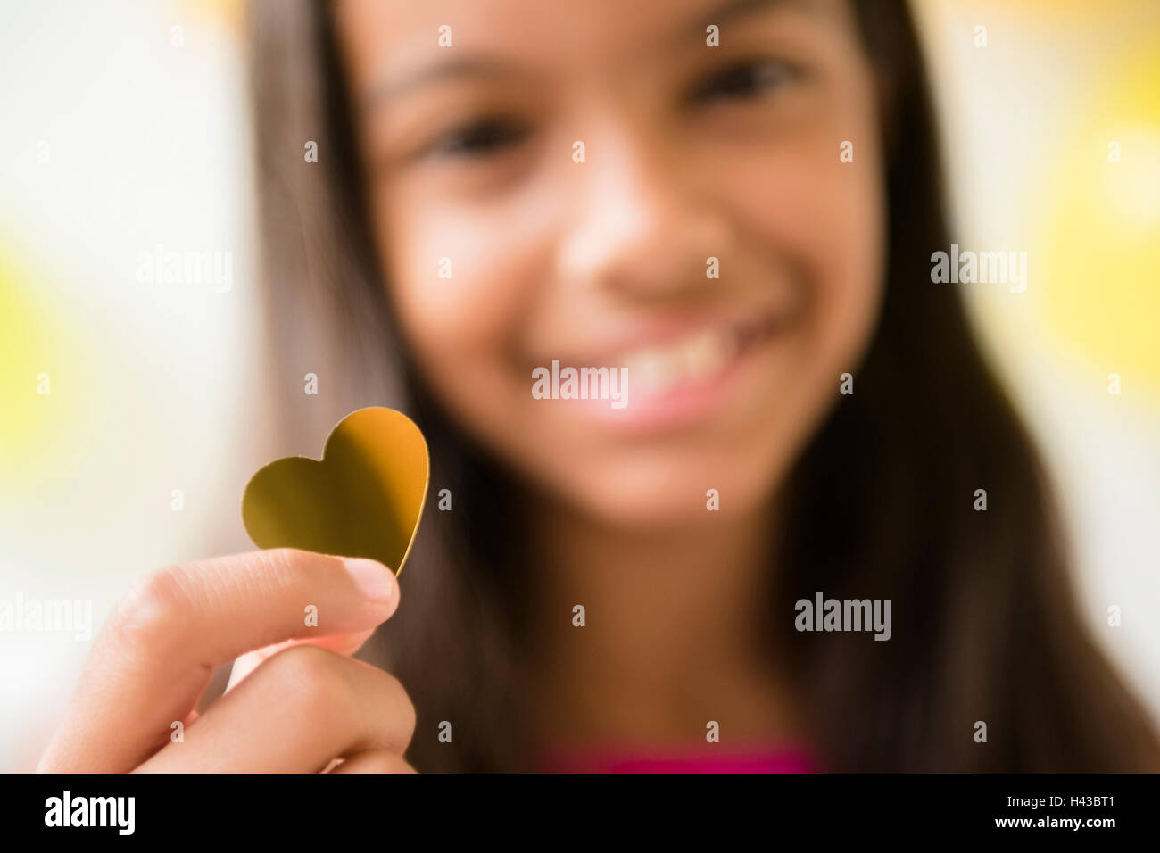 Mixed Race girl holding golden heart-shape confetti Banque D'Images