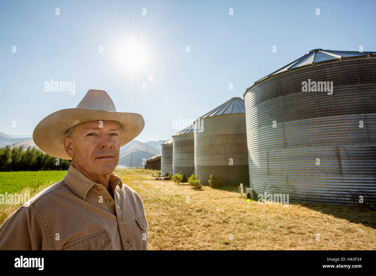 Portrait grave agriculteur près de silos de stockage Banque D'Images