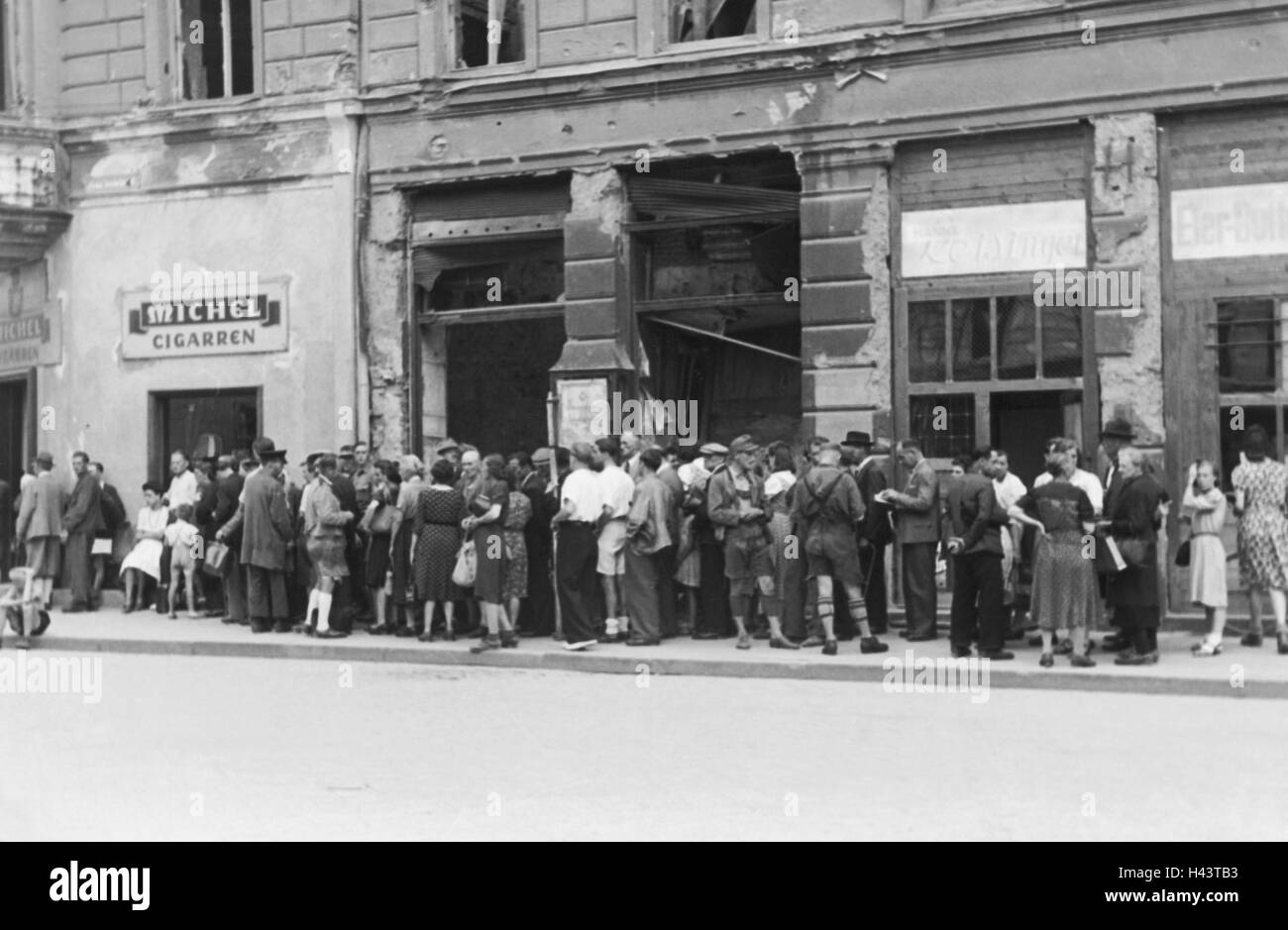 Germany, Bavaria, Munich, des passants, de file d'un tabac, 1947, scène de rue, la ville, la circulation, les transports, les transports publics, les piétons, les gens, debout, en attente, attente, patience, les produits de luxe, rare, de la construction, destruction, Allemagne de l'après-guerre, après-guerre, marché aux bestiaux, le tabac, des dommages matériels, des produits du tabac, des dommages causés par les bombes, les dommages de la guerre, des cigarettes, de la reconstruction, historique, de la nostalgie, à l'extérieur, Banque D'Images