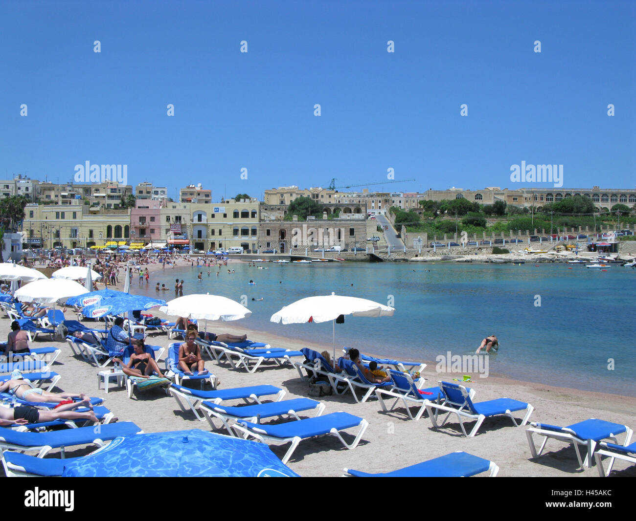 Malte, Sliema, St George's Bay, vue sur la plage, île, île de la Méditerranée, destination, vue sur la ville, le tourisme, la mer, l'eau, la mer Méditerranée, plage de sable, chaises longues, parasols, plage de mensonge, de personnes, les touristes, les baigneurs, vacances, vacances, plage, vacancier Banque D'Images