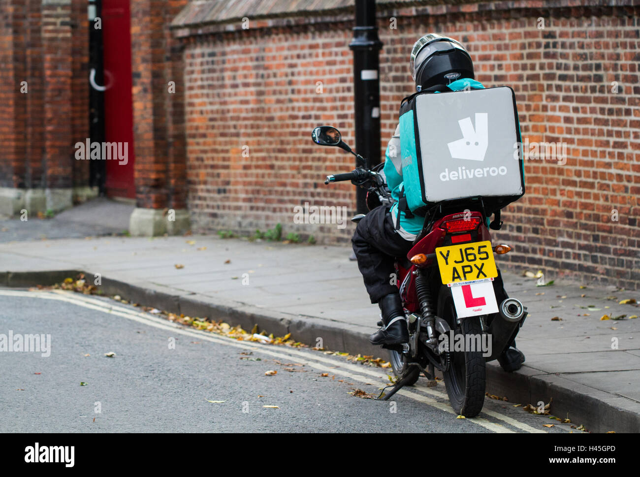Un deliveroo motocycliste de la plus populaire des aliments chauds et fast food delivery company sans rouler pour un ordre. Banque D'Images