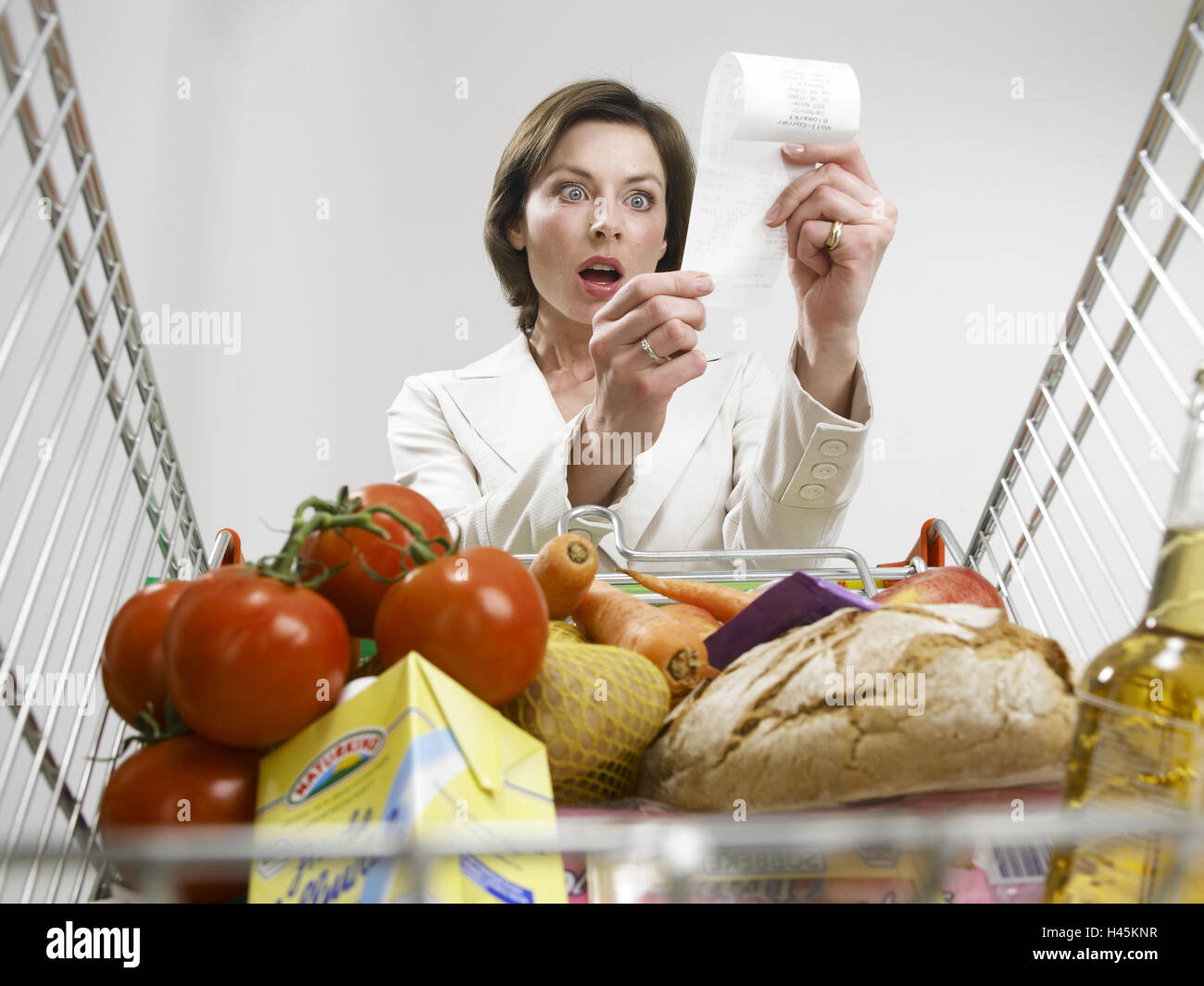 Femme, horrifie, bordereaux de vente, regardez, perspective, panier, portrait, femme au foyer, personne, client, l'inflation, faire des achats, le panier de biens, chargée, complètement, farci, nourriture, bon de réduction, les montants, les prix, se lit, de la nourriture, des biens, l'achat, la conception, l'augmentation des prix, augmentation des prix, augmentation des prix, les dépenses, l'augmentation des coûts, hausse de prix, la demande de la vie, jouer du visage, surprises, affectée, studio, Banque D'Images