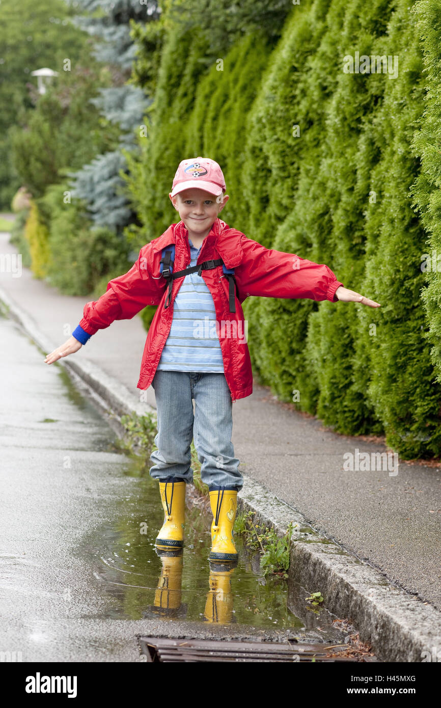 Un garçon, 5 ans, avec des vêtements de pluie, extérieur, Banque D'Images