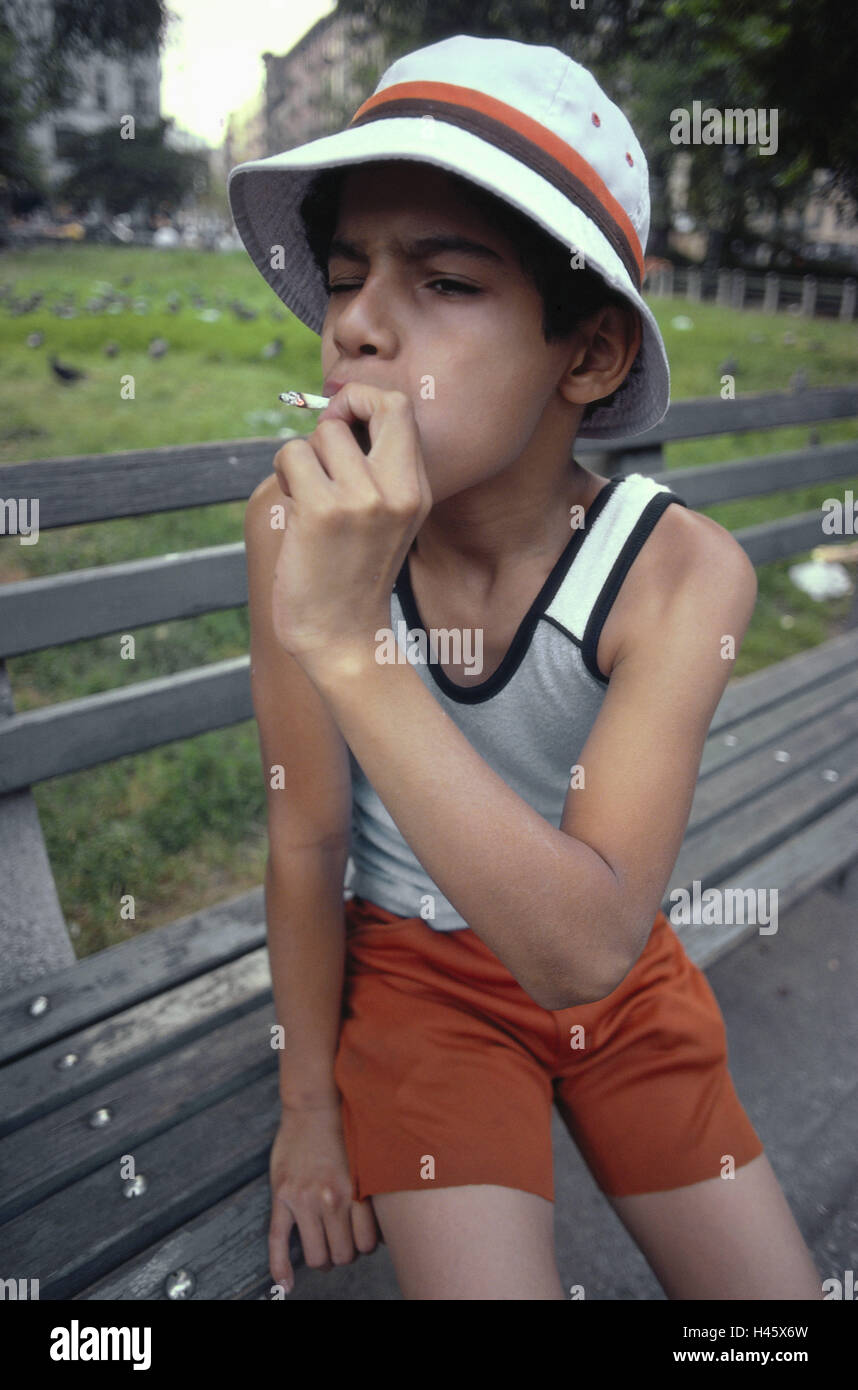 Les USA, New York City, garçon, fumée, cigarette de marihuana, Manhattan, à la prise de médicaments, drogues, coiffures, soins, banc de parc, prairie, illégalement, à l'extérieur, Banque D'Images