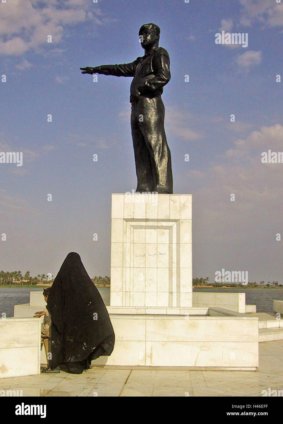 13 avril 2003 une femme irakienne se distingue avec son enfant en dessous d'une statue de Saddam Hussein dirigé vers l'Iran sur le Chatt al-Arab à Bassorah. Banque D'Images